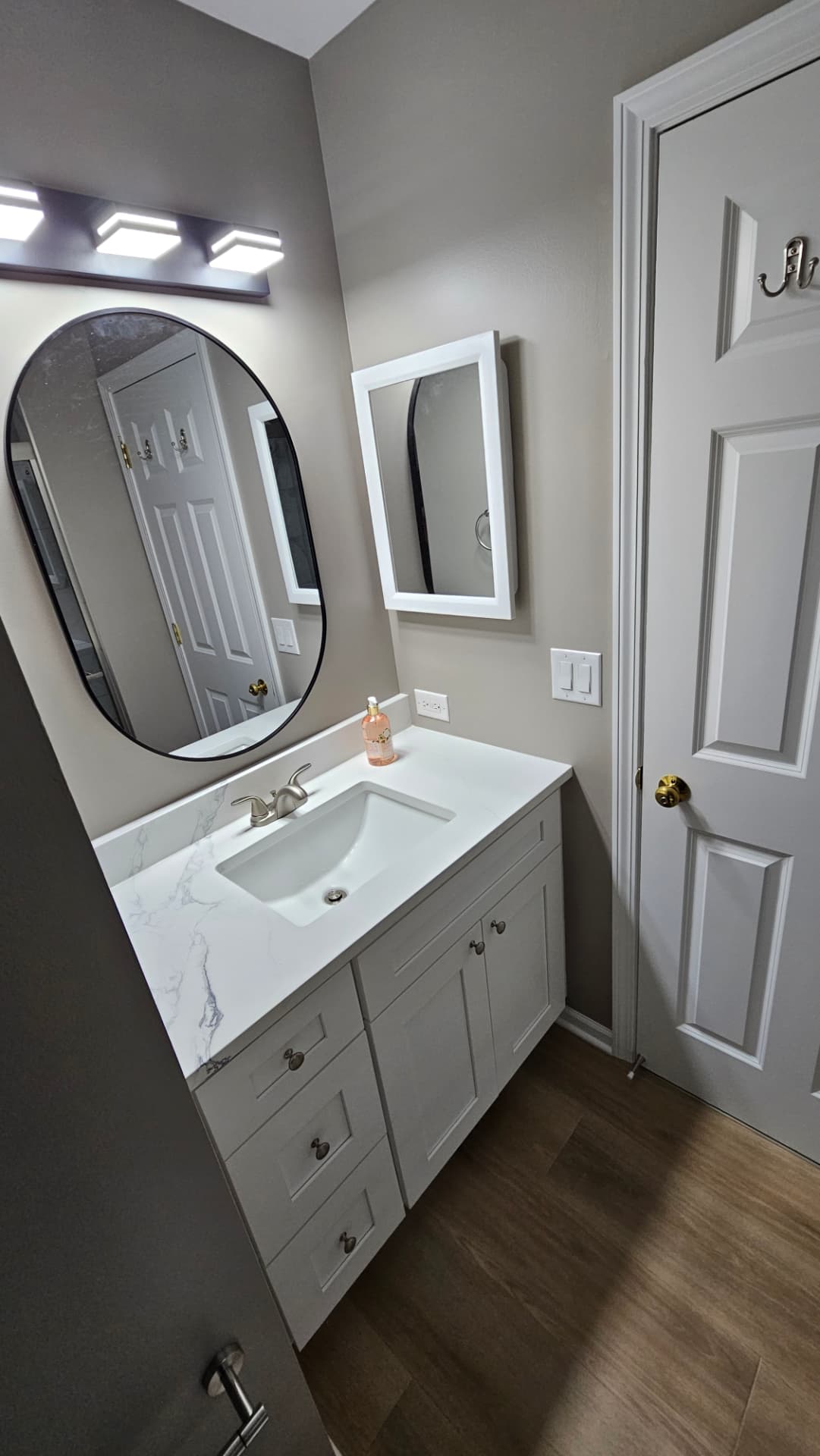 Matching bathroom vanity with quartz top, round black mirror and brushed nickel fixtures