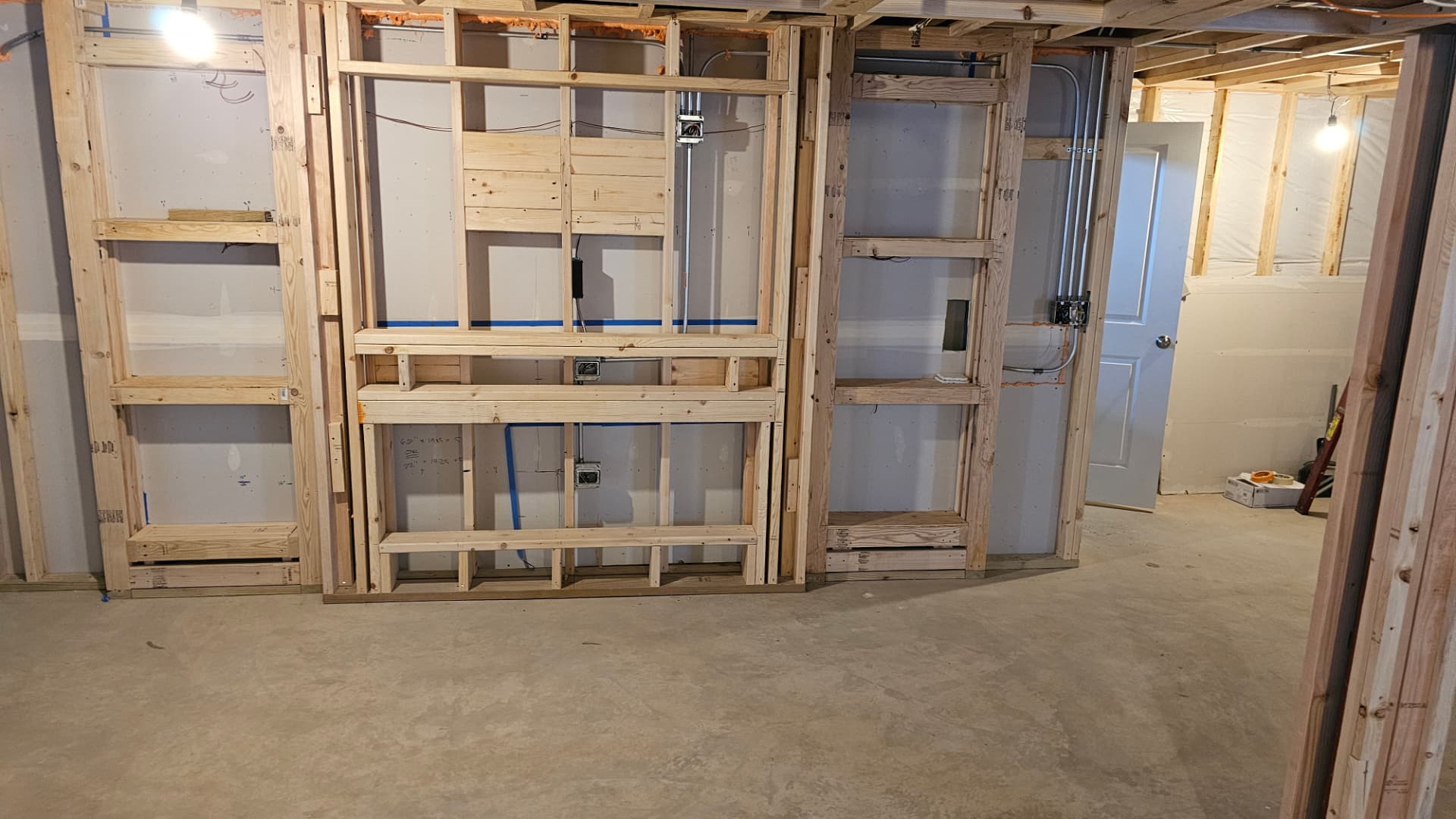 Framed built-in wall with stud shelving bays and rough electrical during construction