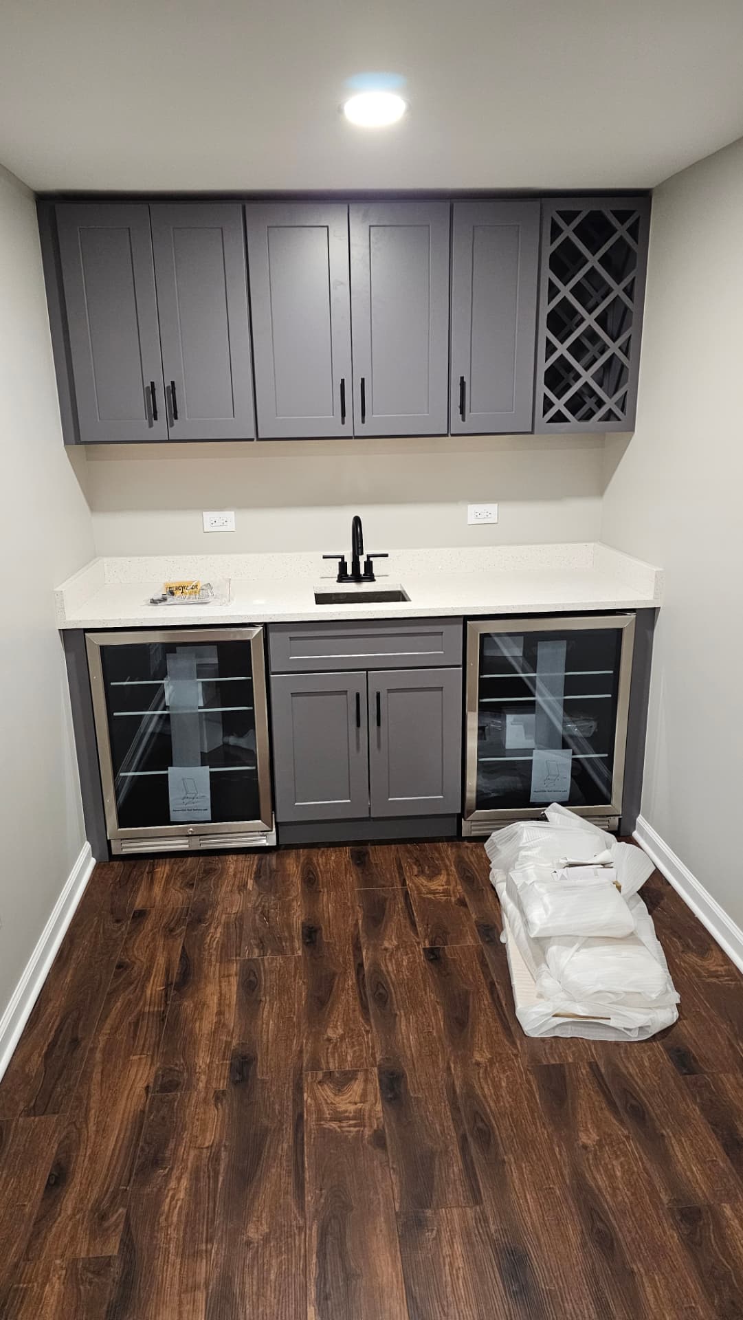 Wet bar with grey shaker cabinets, wine rack, quartz counter, bar sink and two beverage coolers