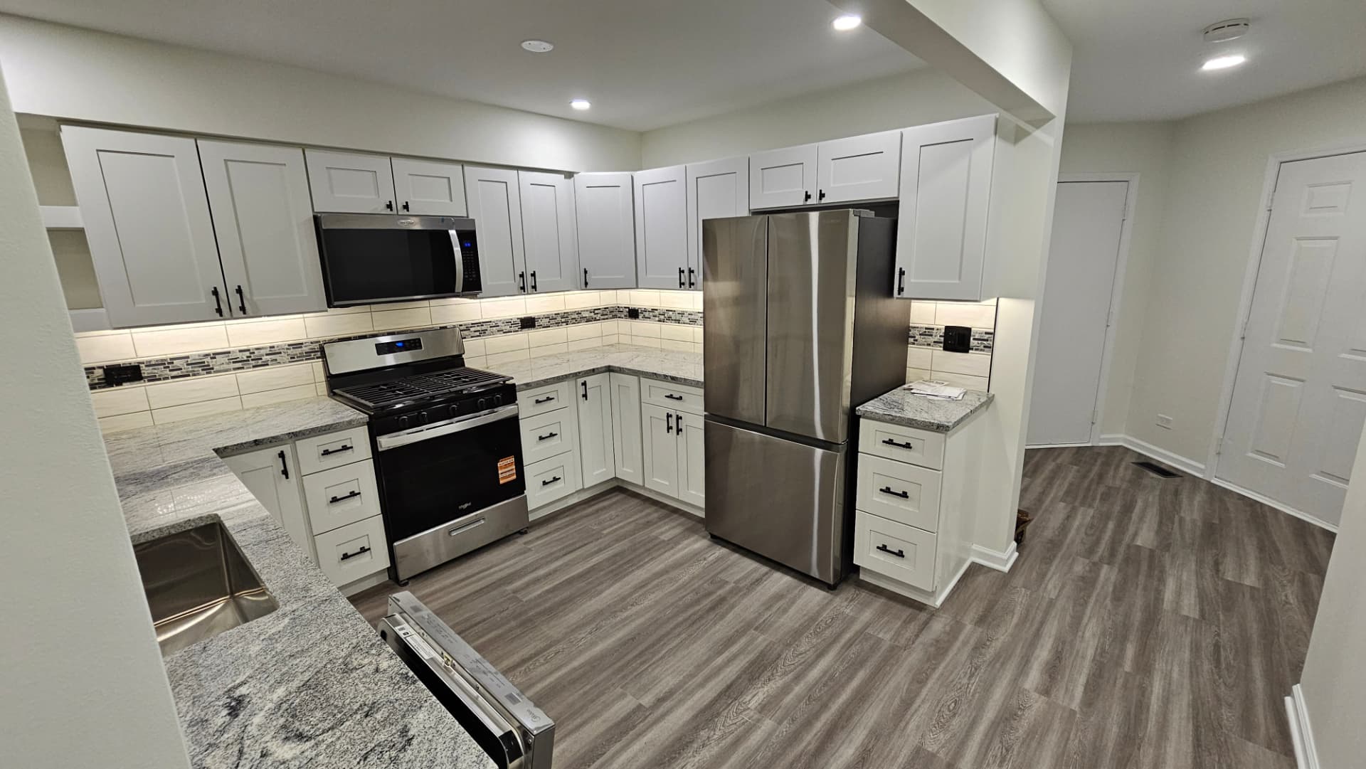 Finished kitchen with white shaker cabinets, granite counters, tile backsplash and stainless appliances