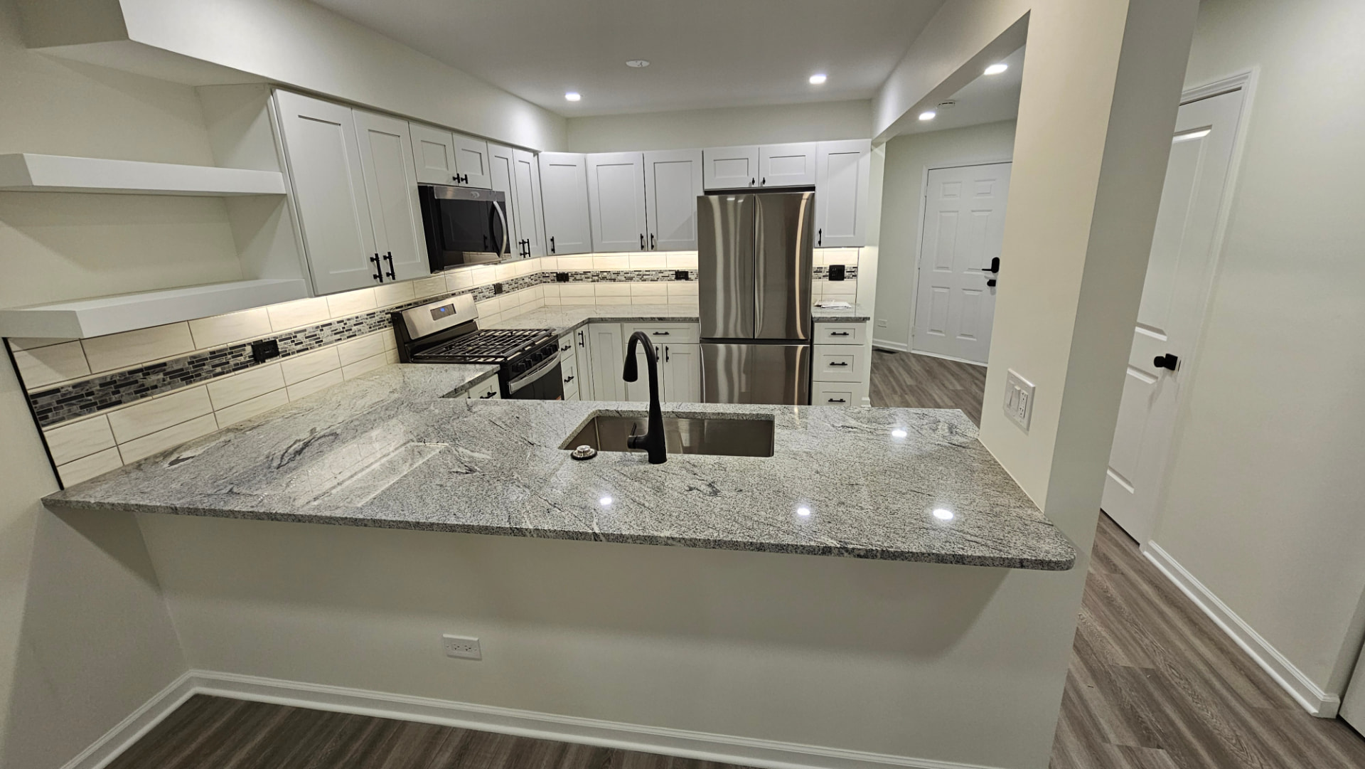 Finished kitchen with white shaker cabinets, granite counters and a tiled backsplash