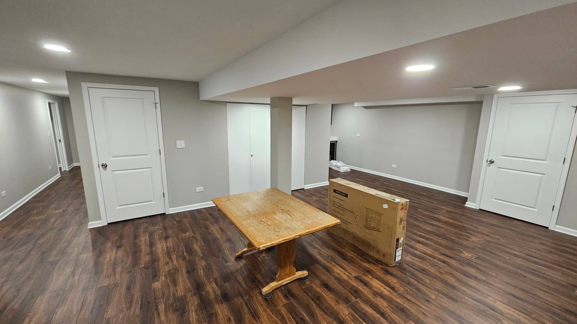 Finished lower level with painted walls, white doors and dark plank flooring