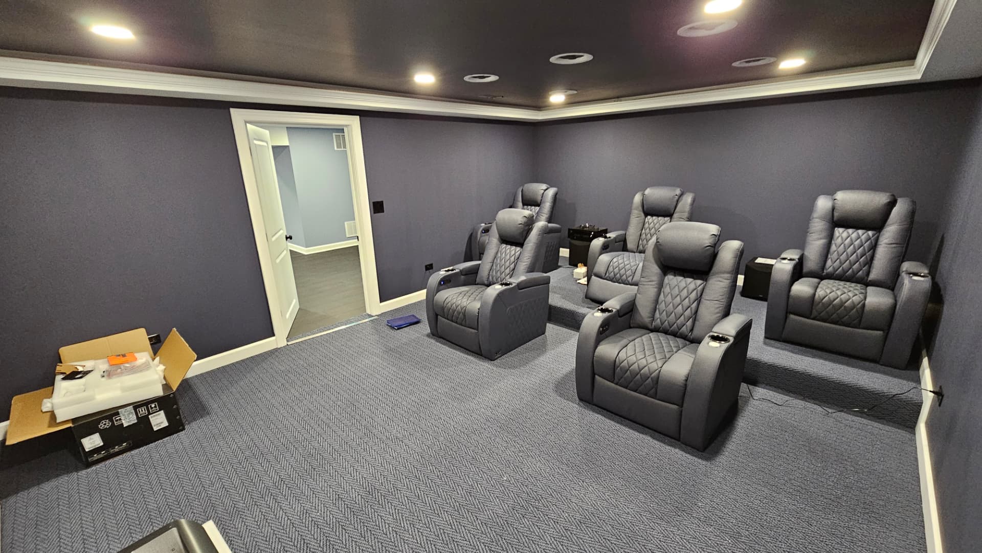 Finished home theater room with tiered recliner seating, carpet and crown moulding