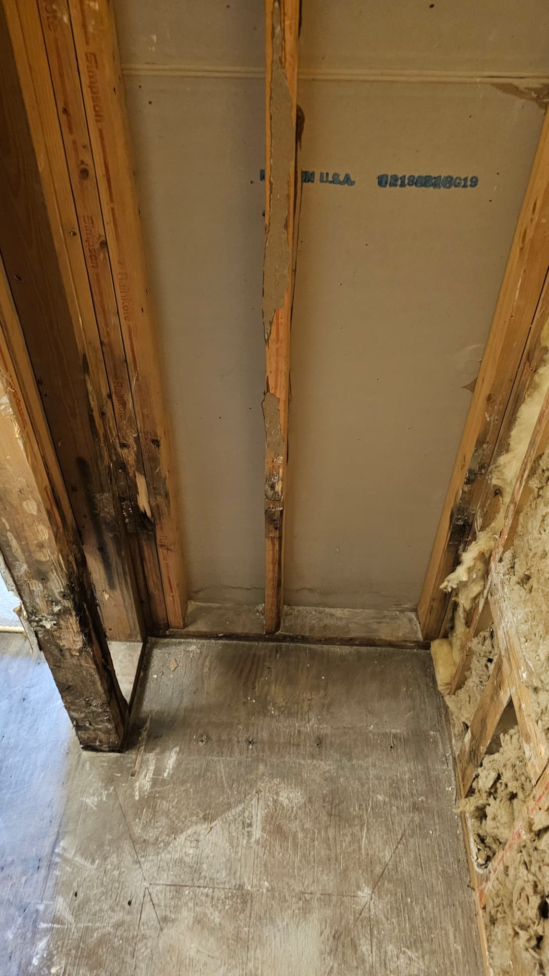 Wall opened up during demolition showing water-damaged framing and subfloor
